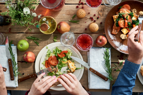 Tisch aus der Vogelperspektive mit vegetarischem Essen und den Händen mehrerer Personen